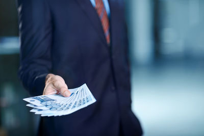 Midsection of businessman giving money