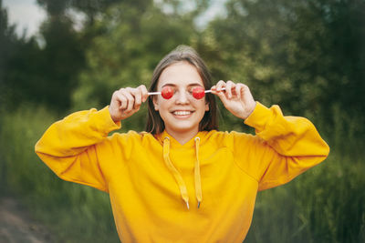 Smiling girl holding lollipops while standing against plants in park