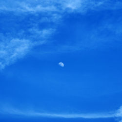 Low angle view of moon in blue sky