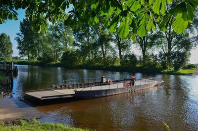 People in boat on river against trees