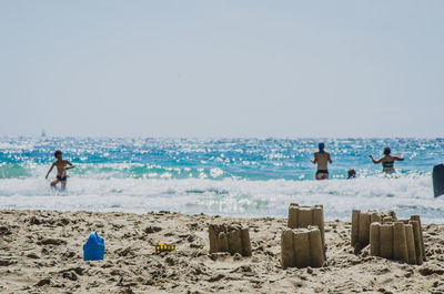 People swimming in ocean against clear sky