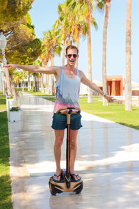 Portrait of young man wearing sunglasses standing against trees