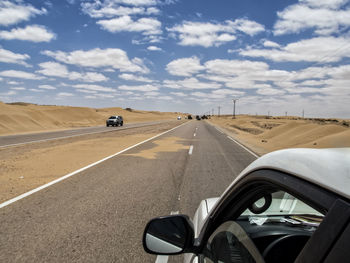 Car on road against cloudy sky