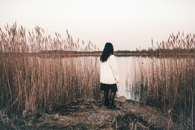 Rear view of woman standing by plants against sky