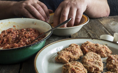 Cropped image of hands mixing batter by minced meat at table