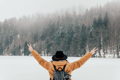 Rear view of woman standing by frozen lake. winter, arms outstretched, adventure, freedom.