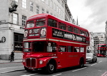 Red cars on road against sky in city