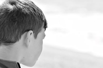 Close-up of boy looking away against sky