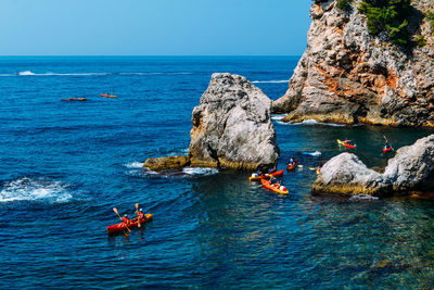 High angle view of people kayaking on sea against sky