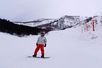 Man snowboarding on snowcapped mountain at niseko