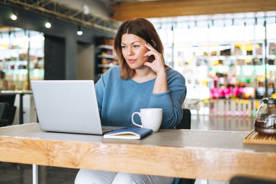 Beautiful stylish young woman plus size body positive using laptop at the beauty salon office