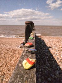 Wooden post on sand at beach against sky