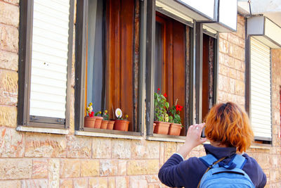 Full length of woman using mobile phone against building