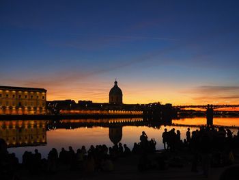 Group of silhouette people in front of building at sunset