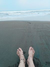 Low section of woman sitting at beach