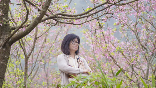 Portrait of young woman standing against trees