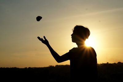 Silhouette man playing against sky during sunset