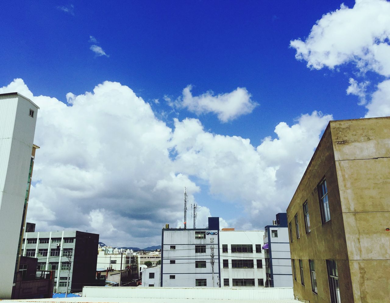 building exterior, architecture, built structure, sky, low angle view, cloud - sky, building, city, blue, cloud, residential building, residential structure, day, cloudy, outdoors, tower, house, no people, window, sunlight