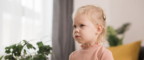 Close-up of cute girl looking away while standing at home