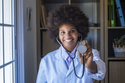 Portrait of smiling doctor showing stethoscope at clinic