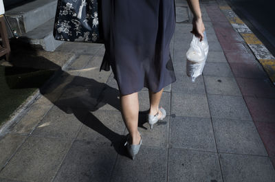 Low section of woman walking on sidewalk