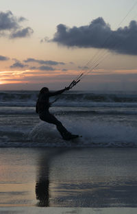 Silhouette man on beach against sky during sunset