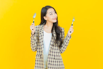 Portrait of smiling young woman against yellow background