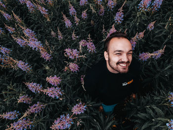 Portrait of smiling young woman against purple flowering plants