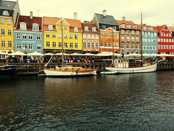 Boats moored on river by buildings in city