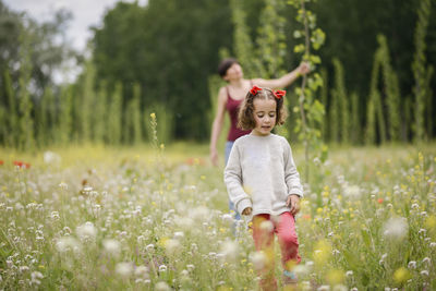 Full length of mother and daughter walking on field