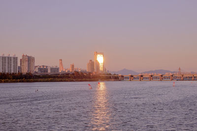 City by sea against clear sky during sunset