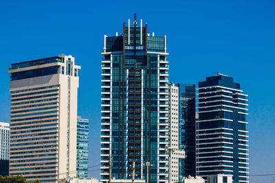 Low angle view of modern buildings against blue sky