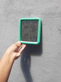 Close-up of person holding camera against wall