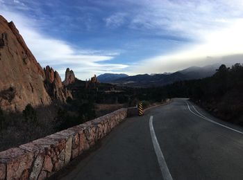 Road leading towards mountains against sky