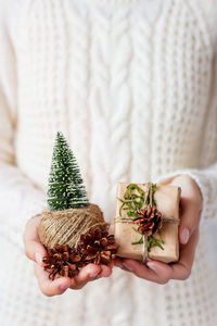 Woman holds present, linen rope, toy christmas tree. diy way to wrap christmas, new year presents.