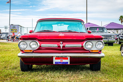 Red vintage car on land against sky