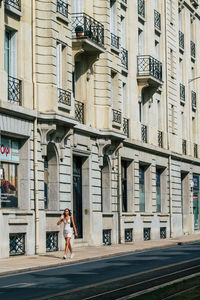 Woman walking on road amidst buildings in city