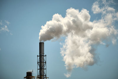 Low angle view of smoke emitting from chimney against sky