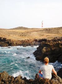 Rear view of woman standing on beach against clear sky