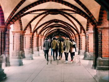 Full length rear view of people walking in building corridor