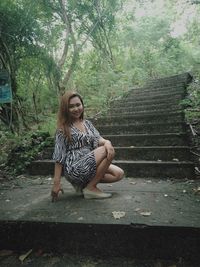 Woman sitting on staircase in forest