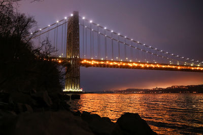 Illuminated suspension bridge over river at night