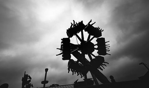 Low angle view of ferris wheel against cloudy sky