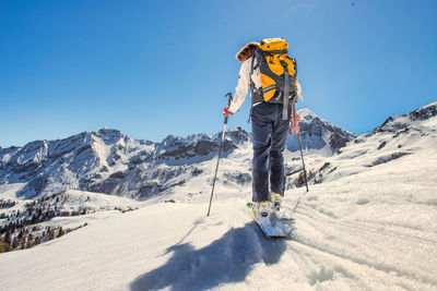 Rear view of man skiing on snowcapped mountain against sky