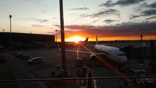 Airplane on runway against sky during sunset