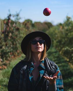 Young woman wearing sunglasses standing against plants