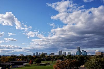 Trees and buildings against cloudy sky