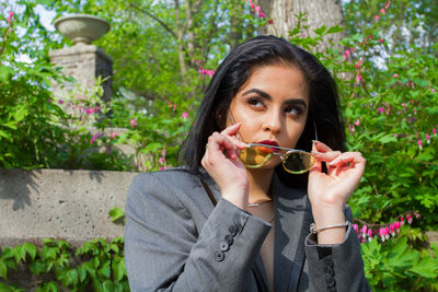 Businesswoman wearing sunglasses looking away against plants outdoors