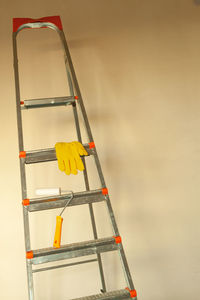 Yellow work gloves on a stepladder against the background of an empty wall. 