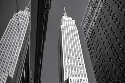 Low angle view of empire state building reflecting on glass